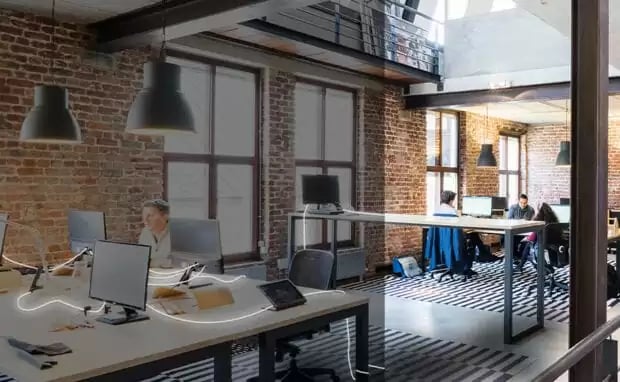 Modernes Grossraumbüro im Loft-Stil mit Backsteinwänden, offenen Arbeitsplätzen und zeitgemässer Büroeinrichtung