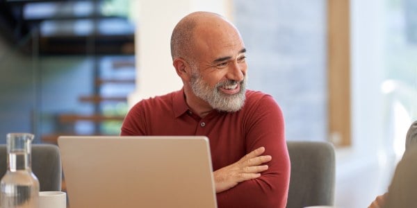IT-Fachmann in modernem Schweizer Büro lächelt während Gespräch vor Laptop – Thema Aruba Zero Trust und Cybersicherheit im Unternehmensumfeld.