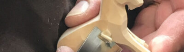 Detailaufnahme einer Hand, die ein hölzernes Trauffer-Spielzeugpferd hält – traditionelles Schweizer Holzspielzeug mit Schnitzkunst aus dem Berner Oberland.